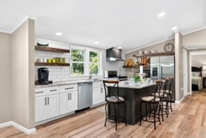 A modern kitchen with white cabinets, a central island with bar stools, and a built-in oven. - Southern charm at its best (Crossville)