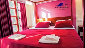 Quarto de hotel com uma cama grande, roupa de cama vermelha e um logotipo na parede.