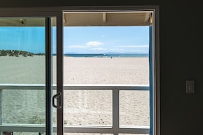 Une vue sur la plage à travers une porte vitrée, une poignée en métal et un interrupteur sur le mur.