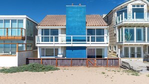 Una proprietà sul lungomare con una struttura verticale blu ben visibile, un balcone e una zona terrazzata coperta.