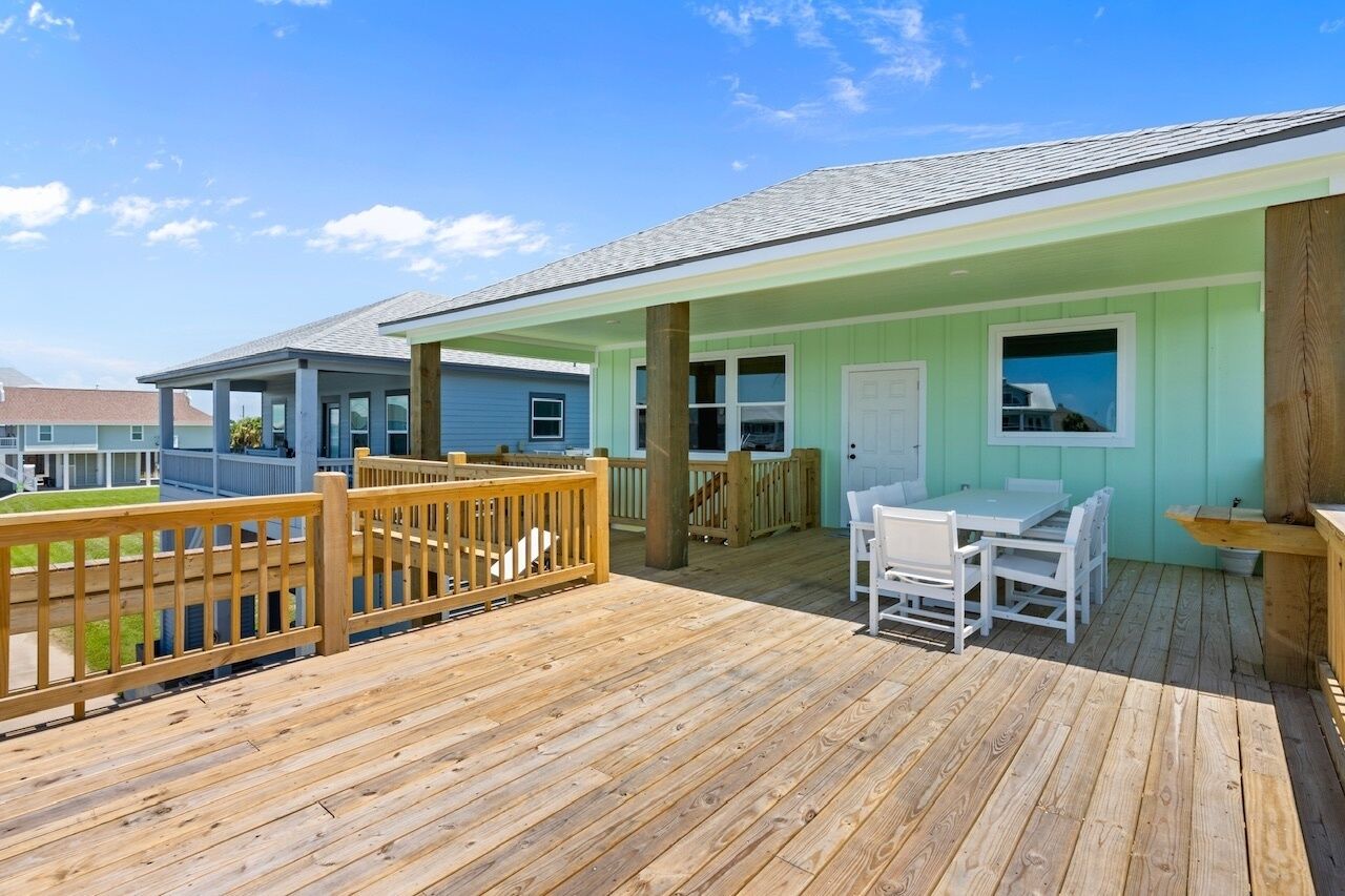 A wooden deck with a covered seating area, a door, and a window.