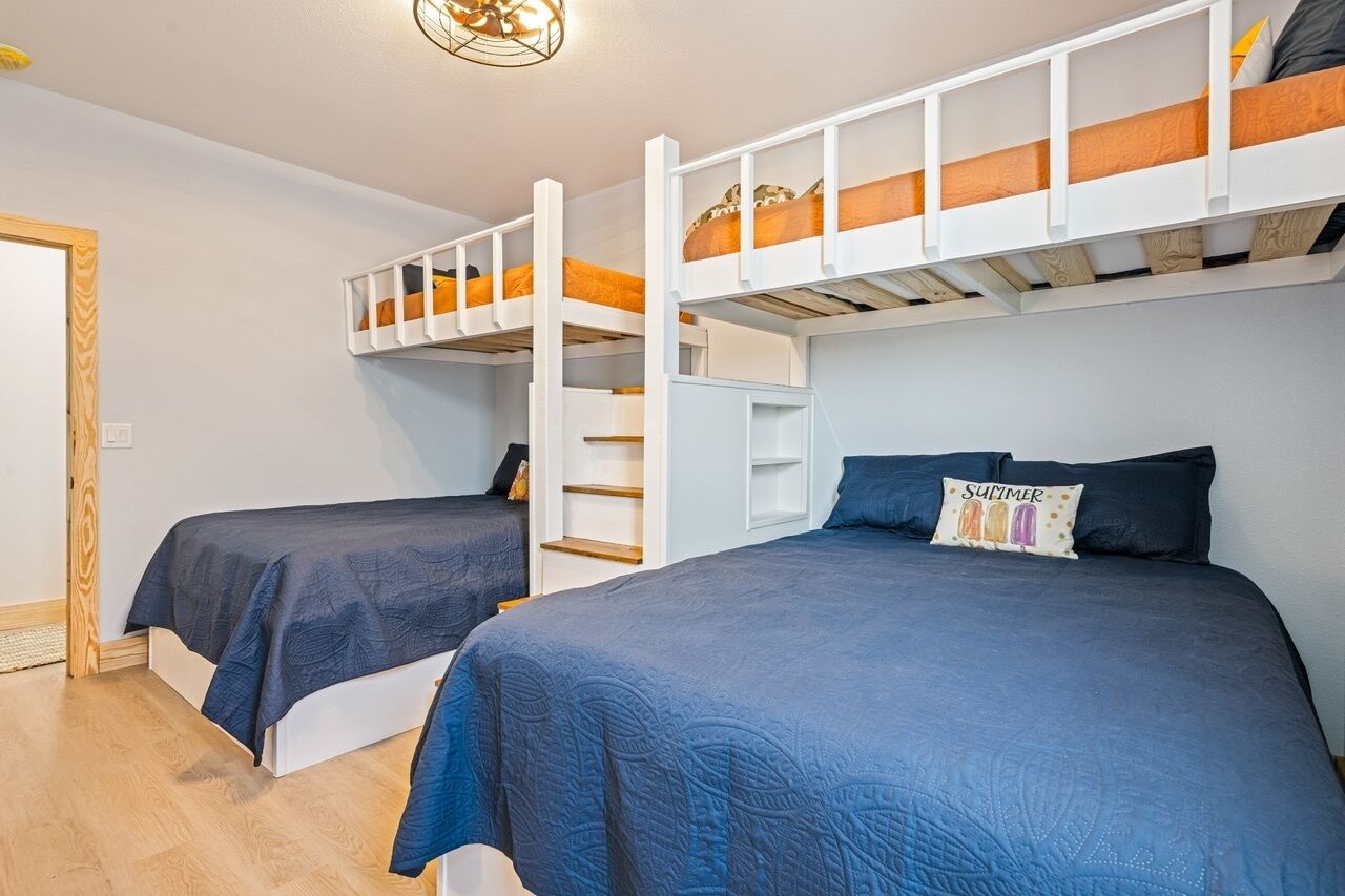 Ein Zimmer mit Stockbetten, einer kleinen Treppe und einem Kissen mit der Aufschrift 'SUMMER'.