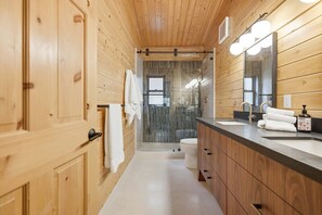 A wooden-paneled bathroom with a shower, a sink, and a mirror. - Log Cabin With Shou Sugi Ban Fireplace - Vh401 4 Bedroom Home (Arnold)