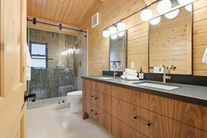 A modern bathroom with wooden paneling, a large mirror, and a glass shower enclosure. - Log Cabin With Shou Sugi Ban Fireplace - Vh401 4 Bedroom Home (Arnold)