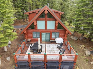 A log cabin with a deck, outdoor seating, and a covered patio area. - Log Cabin With Shou Sugi Ban Fireplace - Vh401 4 Bedroom Home (Arnold)