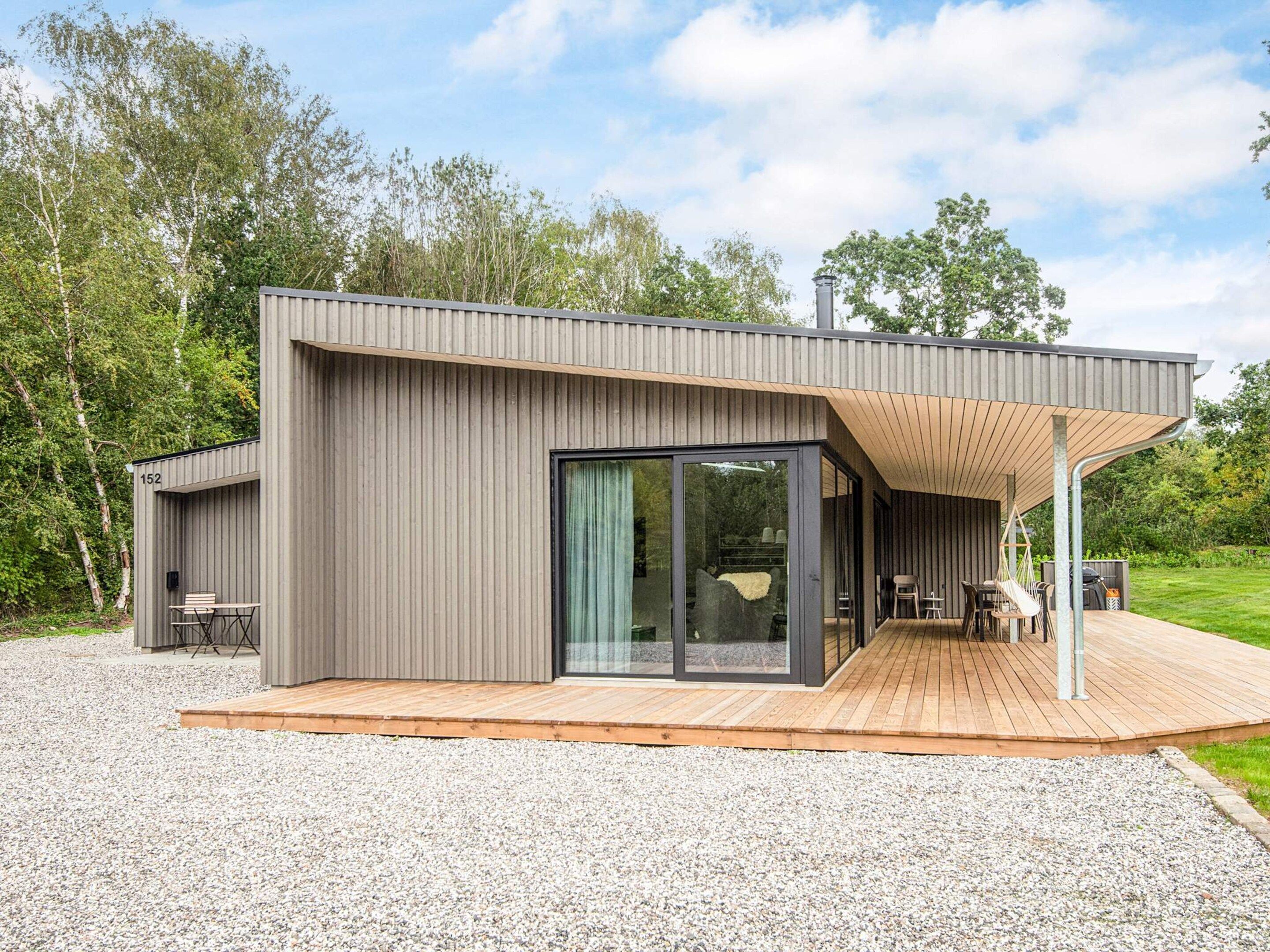 A modern house with a deck, a covered outdoor seating area, and a large sliding glass door.