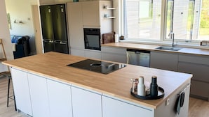 Una cocina moderna con una isla central, electrodomésticos integrados y un amplio ventanal.