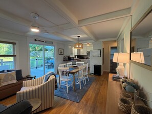 A modern kitchen with white cabinets, a dining area with a table and chairs, and a living room with a sofa and a coffee table.