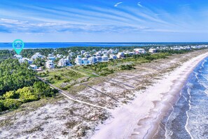 Une zone côtière comprenant une plage, une route et un quartier résidentiel avec des maisons.
