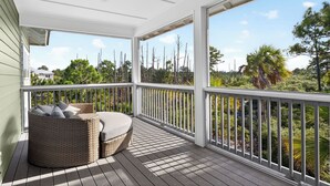 A covered porch with a wicker sofa and cushions, white railings, and a view of a natural landscape. - Gulf View Pool | Deeded Beach Access | Jubilation | Sleeps 11, Boat Parking (Pot St Joe)