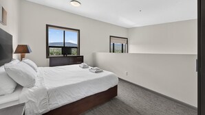 A bedroom with a bed, a TV, and a window with a view. - 2 Bd Loft 603 @ Playa. Pool & Hot Tub (Kelowna)
