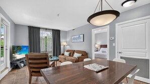 Hotellihuone, jossa on puinen ruokapöytä, sohva, televisio ja sänky.
