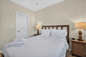 Ein Hotelzimmer mit einem Bett, zwei Nachttischen, einer Tür und einer Deckenleuchte.