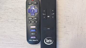 Dos controles remotos, uno con un botón azul y el otro con un logo blanco.