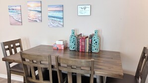 A dining area with a wooden table and chairs, a wall with three framed pictures, and a decorative bottle on the table. - Bayside Coastal Retreat Near Copano Bay (Bayside)