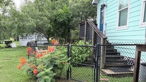 A residential property with a fenced yard, a wooden staircase, and a house with light blue siding. - Bayside Coastal Retreat Near Copano Bay (Bayside)
