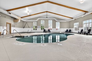 Ein überdachter Pool mit hoher Decke, Holzbalken und Sitzbereichen.