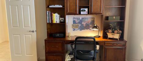 A home office desk with a computer, chair, and various office supplies.