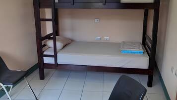 A bunk bed with a ladder, a chair, and a desk in a room with tiled flooring.