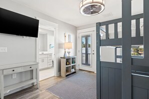 A modern interior with a flat-screen TV, a wooden console, a lamp, and a patterned rug. - Blue Horizon, Pool, Beach, Golf Cart (Santa Rosa Beach)