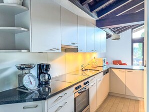 Eine moderne Küche mit weißen Schränken, einer schwarzen Arbeitsplatte, einer Kaffeemaschine und einem Backofen.