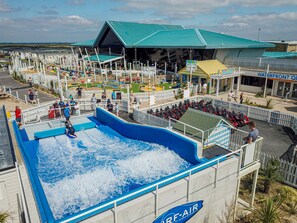 A water park with a wave pool, seating areas, and a building with a green roof. - Sunny Nook Cozy Cabin Retreat Selsey, Gated Garden (Chichester)
