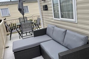 A covered outdoor seating area with a sofa and chairs, a table, and a grill. - Sunny Nook Cozy Cabin Retreat Selsey, Gated Garden (Chichester)