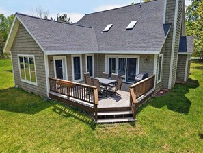 Ein Haus mit einer Terrasse, einem Esstisch und Stühlen.