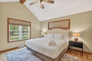 Quarto com uma cama, duas mesas de cabeceira, um ventilador de teto e uma janela com persianas.