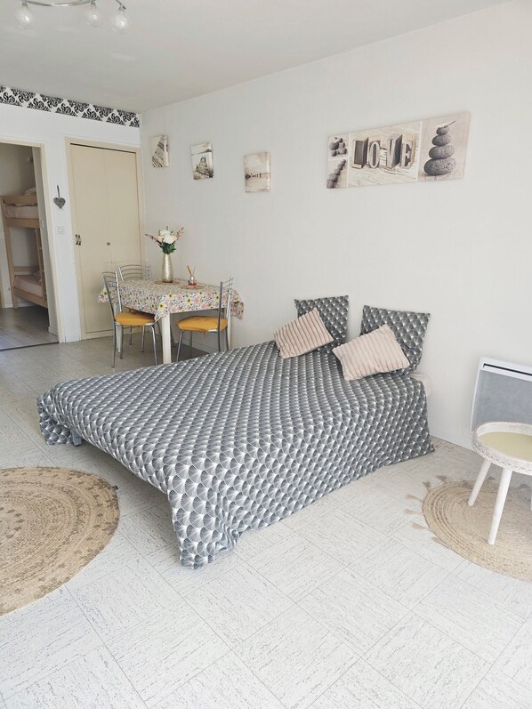 A bedroom with a bed, a dining table, and a chair.