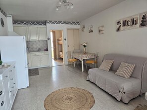 Un espacio habitable compacto con kitchenette, comedor y sofá.