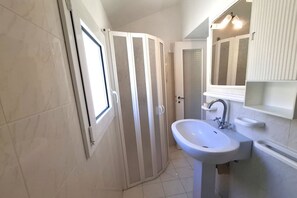 A bathroom with a shower, a sink, and a mirror. - Losanna Apartment (La Pila)