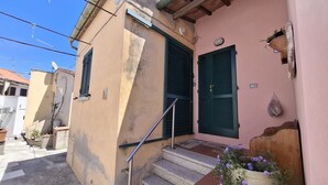 Uma rua estreita com um edifício que apresenta uma escadaria, uma porta e um vaso de planta.