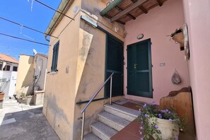 Eine enge Straße mit einem Gebäude, das eine Treppe, eine Tür und einen Blumentopf zeigt.