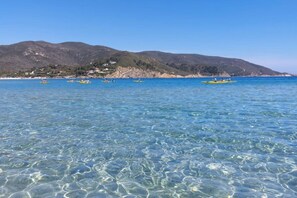 Clear water, a beach, and mountains in the background. - Losanna Apartment (La Pila)