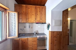Eine Küche mit Holzausstattung, einem Edelstahlspülbecken und einem Einbauofen.