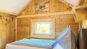 Una camera in legno con un letto, una finestra e un quadro appeso al muro.