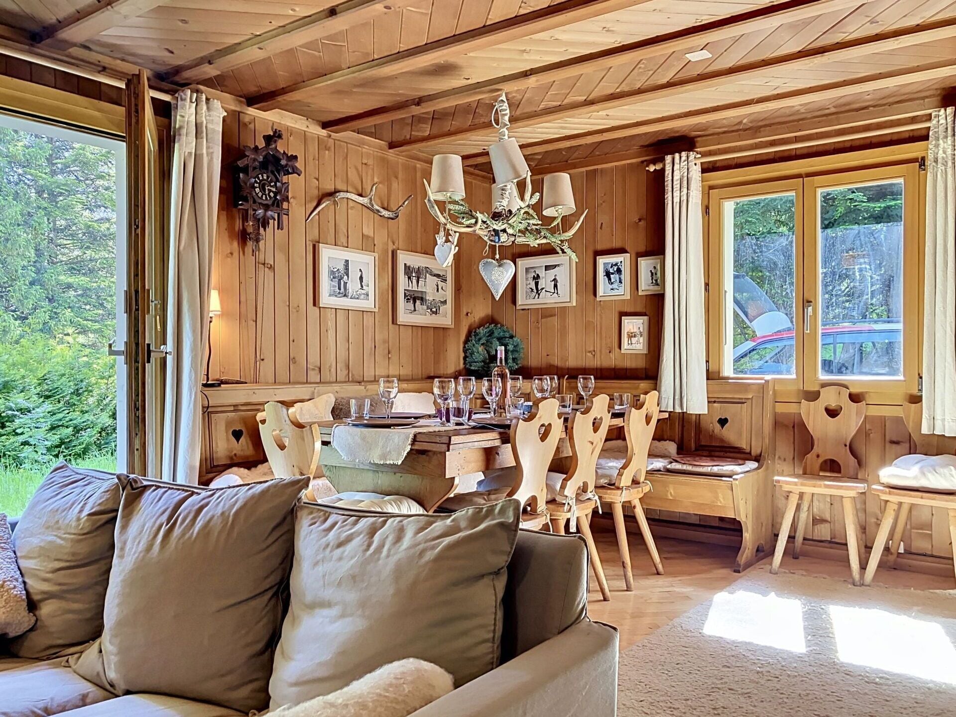 Ein Holzinnenraum mit einem für sechs Personen gedeckten Esstisch, einer Couch und einer Chandelier.