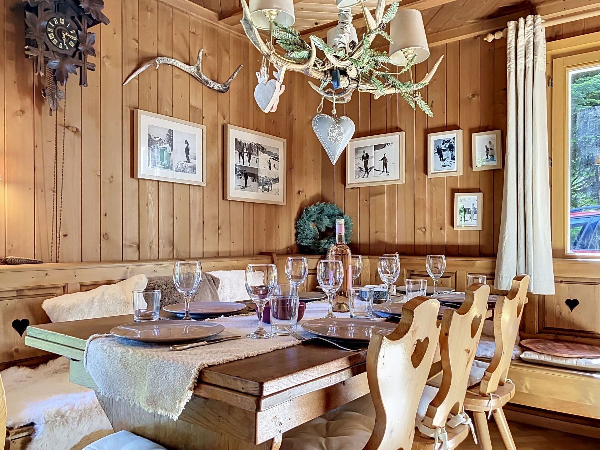 Ein Holzinterieur mit einem für sechs Personen gedeckten Esstisch, gerahmten Bildern an der Wand und einer Chandelier.