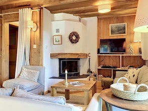 Ein gemütliches Wohnzimmer mit Kamin, Holzwänden, einem Fernseher und einer komfortablen Sitzecke.