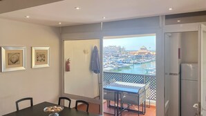 A balcony with a view of a marina, a dining table with chairs, and two framed pictures on the wall. - Duplex Marina Plaza | T1 HsRentals (Vilamoura)