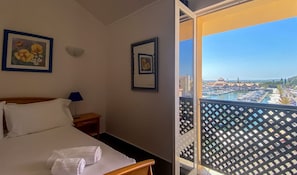 Et hotelværelse med en seng, et natbord, en lampe og to billeder i rammer på væggen.
