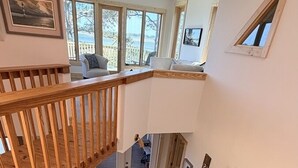 Eine geräumige Küche mit Marmorarbeitsplatte, einer Holztreppe und großen Fenstern mit Blick ins Freie.