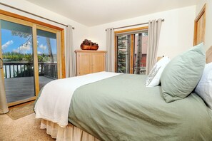 A bedroom with a bed, a wooden cabinet, and a view of a deck and trees. - New!Quiet Shore Chalet-Cozy 3Bed/1.5Bath Home on the Shores of Columbine Lake (Grand Lake)