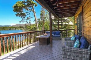 Eine Holzterrasse mit Tisch und Korbmöbeln mit Blick auf einen See.