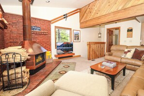 Ein gemütliches Wohnzimmer mit Kamin, Ledersofa und Fernseher.