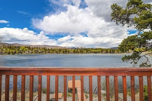 Un lago con una terrazza in legno e vista su una zona boschiva.