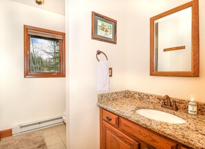 A bathroom with a granite countertop, a sink, a mirror, and a window with a view of trees. - New!Quiet Shore Chalet-Cozy 3Bed/1.5Bath Home on the Shores of Columbine Lake (Grand Lake)
