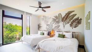 Camera da letto con due letti, una ventola a soffitto e un'ampia finestra con vista sul verde.