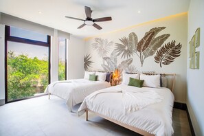 Makuuhuoneessa on kaksi sänkyä, kattotuuletin ja suuri ikkuna, josta on näkymä vehreään maisemaan.